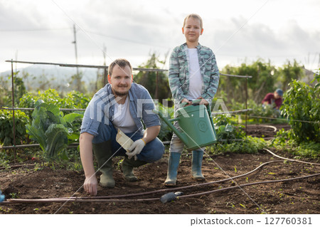 Man and his son planting seeds on a farm 127760381