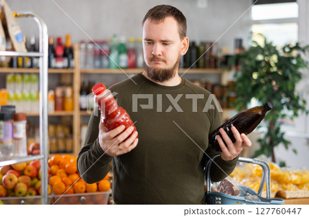 Man choosing juice in the store 127760447