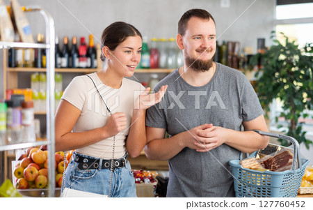 Couple man and woman choosing groceries in store 127760452