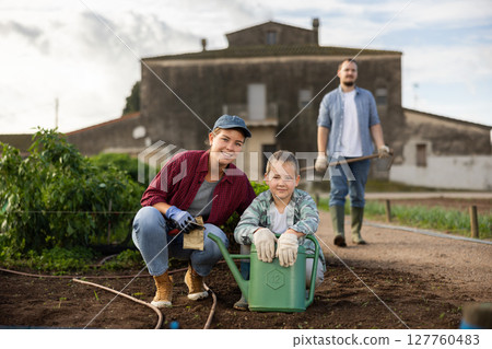 Young woman with boy planting seeds in field 127760483
