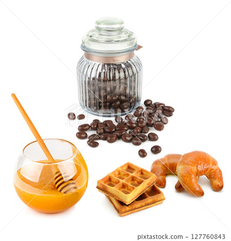Jar with chocolate dragees, honey waffles and croissants isolated on white background. Jar with chocolate dragees, honey waffles and croissants isolated on white background. 127760843