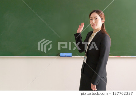 Female teacher standing in front of the blackboard Female teacher standing in front of the blackboard 127762357