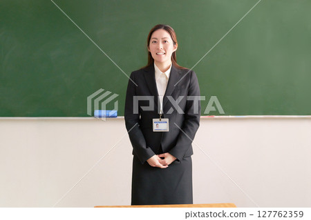 A female teacher standing in front of a blackboard 127762359