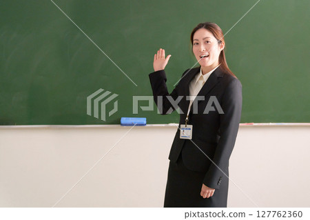 A female teacher standing in front of a blackboard 127762360