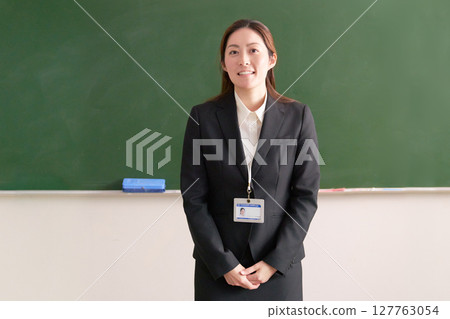 A female teacher standing in front of a blackboard A female teacher standing in front of a blackboard 127763054