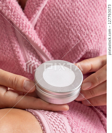 Woman in pink bathrobe holding body butter jar with a label in hands, Closeup, cosmetic mockup 127763073
