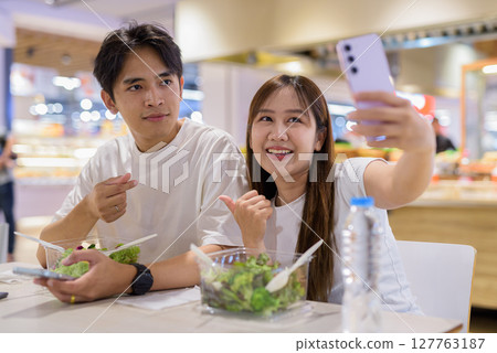Young couple eating salad together 127763187