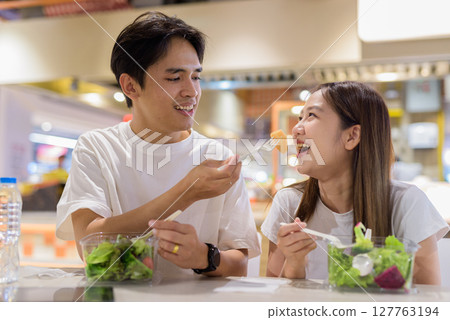 Young couple eating salad together Young couple eating salad together 127763194
