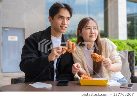 Young Asian couple eating fried chicken Young Asian couple eating fried chicken 127763207