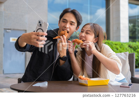 Young Asian couple eating fried chicken Young Asian couple eating fried chicken 127763216