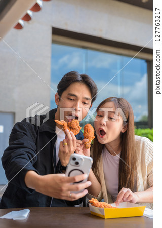 Young Asian couple eating fried chicken Young Asian couple eating fried chicken 127763217