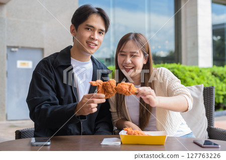 Young Asian couple eating fried chicken Young Asian couple eating fried chicken 127763226