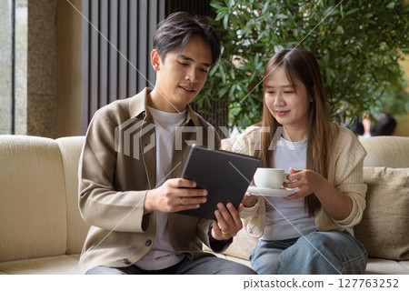 Couple using tablet computer in cafe while having coffee 127763252