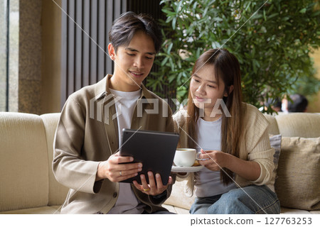 Couple using tablet computer in cafe while having coffee 127763253