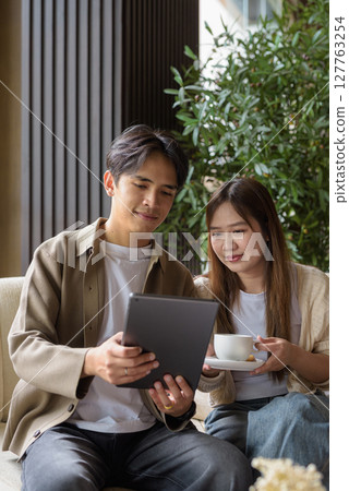 Couple using tablet computer in cafe while having coffee 127763254