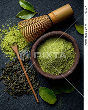 Matcha green tea powder in bowl, bamboo whisk and green tea leaves on black wooden background 127763740