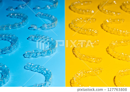 Invisible orthodontic cosmetic aligners on a colored background, aligners, plastic braces. Modern dental retainers created on a 3D printer Invisible orthodontic cosmetic aligners on a colored background, aligners, plastic braces. Modern dental retainers created on a 3D printer 127763808
