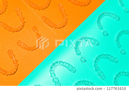 Invisible orthodontic cosmetic aligners on a colored background, aligners, plastic braces. Modern dental retainers created on a 3D printer 127763810
