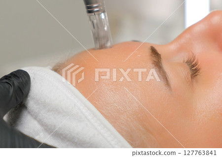 Microneedle RF lifting procedure. A cosmetologist performs a facial rejuvenation procedure on a woman. Hardware cosmetology. Microneedle RF lifting procedure. A cosmetologist performs a facial rejuvenation procedure on a woman. Hardware cosmetology. 127763841