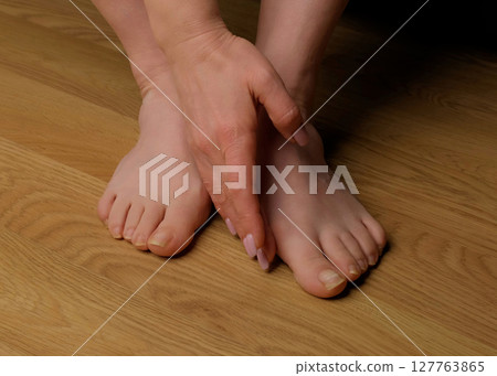 Close-up of a woman s foot with hallux valgus bunion and signs of toenail fungus. Her hand gently touches the deformed big toe, illustrating common foot problems and the need for medical care. Close-up of a woman s foot with hallux valgus bunion and signs of toenail fungus. Her hand gently touches the deformed big toe, illustrating common foot problems and the need for medical care. 127763865