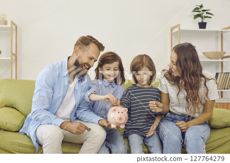 Happy mother, father and children decide to save up and put coins inside piggy bank Happy mother, father and children decide to save up and put coins inside piggy bank 127764279