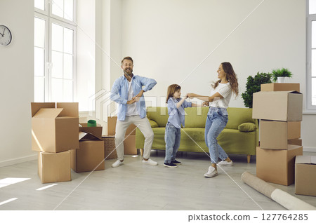 Happy mum, dad and child dancing and having fun in their new house on moving day Happy mum, dad and child dancing and having fun in their new house on moving day 127764285