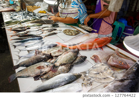 Wide variety of fish displayed on white table at seafood market Wide variety of fish displayed on white table at seafood market 127764422