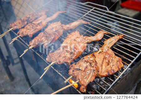 Grilled Chicken on Skewers over Hot Charcoal, Smoking Barbecue Preparation Grilled Chicken on Skewers over Hot Charcoal, Smoking Barbecue Preparation 127764424