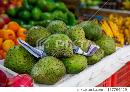 Soursop Guyabano Guanabana Graviola Exotic Green Fruit at Tropical Asian Market with Bananas and Oranges 127764429