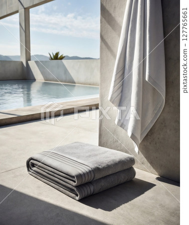 Neatly folded gray gym towel placed at lower center with open white space above shows soft natural fabric texture and shadows for fitness equipment photography 127765661