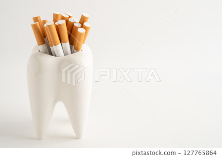 Cigarette in teeth model isolated on white background, damage the health of your teeth, No smoking. Cigarette in teeth model isolated on white background, damage the health of your teeth, No smoking. 127765864