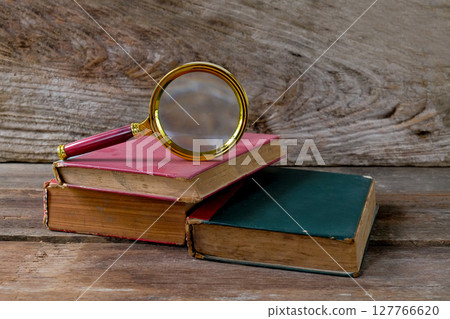 Vintage magnifying glass with old books. Concept for learn history. Vintage magnifying glass with old books. Concept for learn history. 127766620