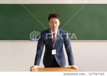 一位男老師站在講台上，表情嚴肅 127767193