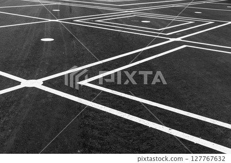A detailed view of intersecting white lines on an asphalt surface, A detailed view of intersecting white lines on an asphalt surface, 127767632