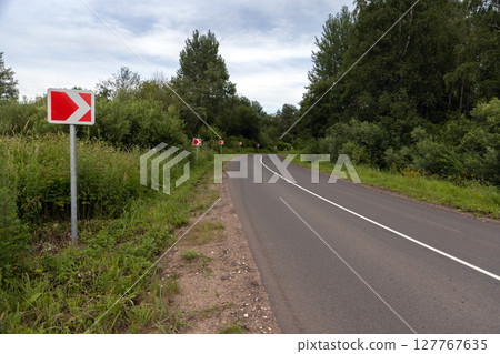A winding road marked with bright road warning signs 127767635