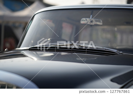 The windshield and chrome wipers of a classic car showcase the timeless allure of vintage automotive design, with their glossy finish and detailed craftsmanship sparking nostalgia for a past era. 127767861