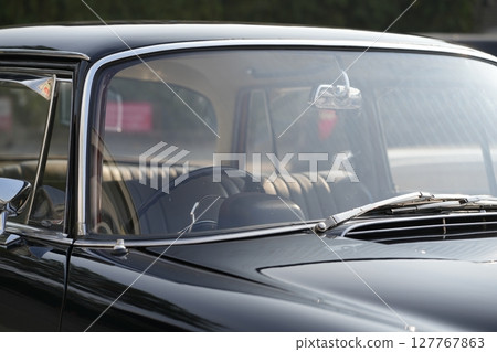 The windshield and chrome wipers of a classic car showcase the timeless allure of vintage automotive design, with their glossy finish and detailed craftsmanship sparking nostalgia for a past era. 127767863