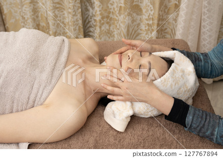 Woman receiving a facial massage 127767894