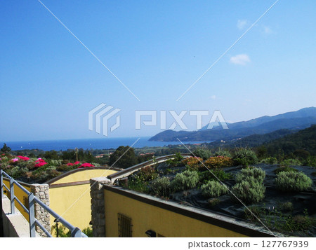 Panoramic distant view of the sea from the island of Elba, Italy, where the deep blue waters stretch like a silk blanket beneath the golden Mediterranean sun. From afar, the coastline curves 127767939