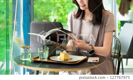 A woman reading a magazine at a cafe A woman reading a magazine at a cafe 127767975