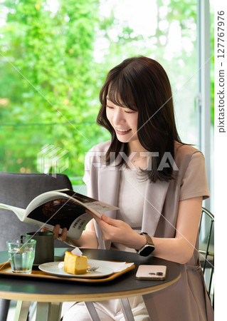A woman reading a magazine at a cafe A woman reading a magazine at a cafe 127767976
