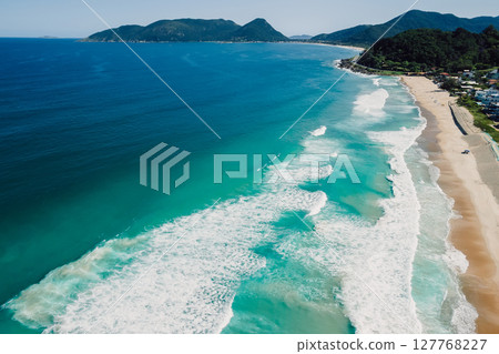 Beach and ocean with surfing waves in Brazil. Drone view of Campeche beach in Floripa 127768227