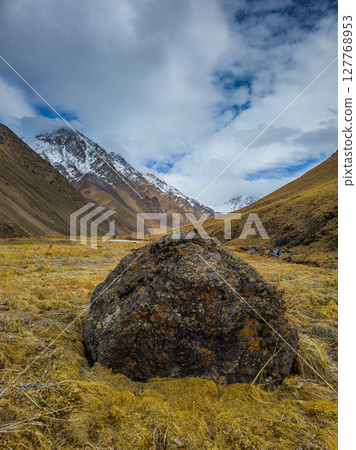 Serene mountain valley with dramatic boulder during daytime in Kyrgyzstan 127768953