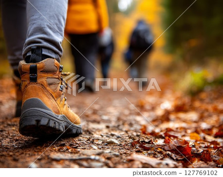 Hiking boots on forest trail with autumn leaves. Ideal for outdoor adventure or nature walks. Adds rugged, earthy feel to travel blogs. 127769102