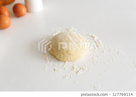 Preparing homemade tagliatelle pasta on on white table: dough and ingredients. Top view Preparing homemade tagliatelle pasta on on white table: dough and ingredients. Top view 127769114