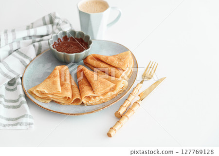 Crepes with chocolate cream and coffee on white wooden table. Pancake day, Maslenitsa 127769128