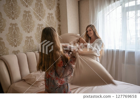 Pillow Fight, Bedroom, Mother Daughter: Playful morning fun between mom and daughter in their bedroom, making the bed. 127769658