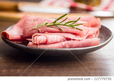Sliced beef pastrami on plate on wooden table. 127770730