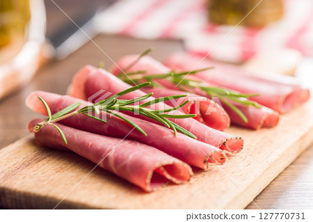 Sliced beef pastrami on cutting board on wooden table. Sliced beef pastrami on cutting board on wooden table. 127770731