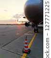 An airplane is currently parked on the runway right next to a traffic cone 127771225